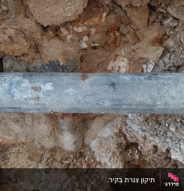 צינור מתכת בתוך קיר עם אדמה חשופה